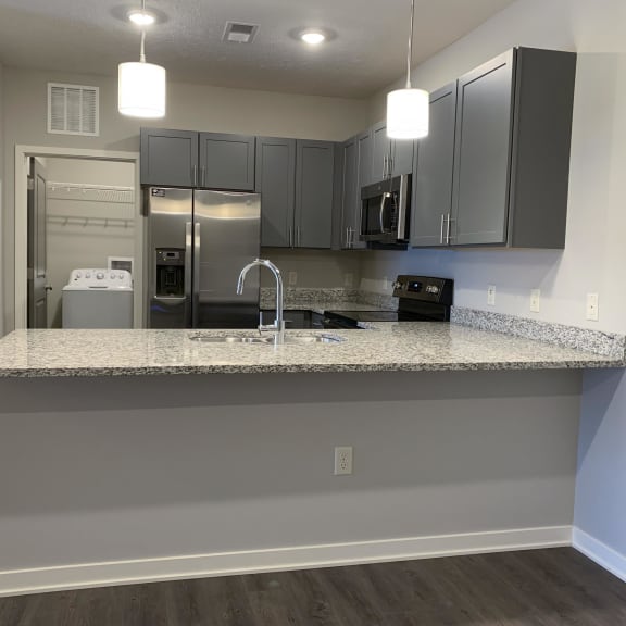 Thumbnail 4 of 21 A kitchen with a granite countertop and stainless steel appliances.