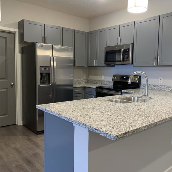 Thumbnail 5 of 21 A kitchen with a granite countertop and stainless steel appliances.