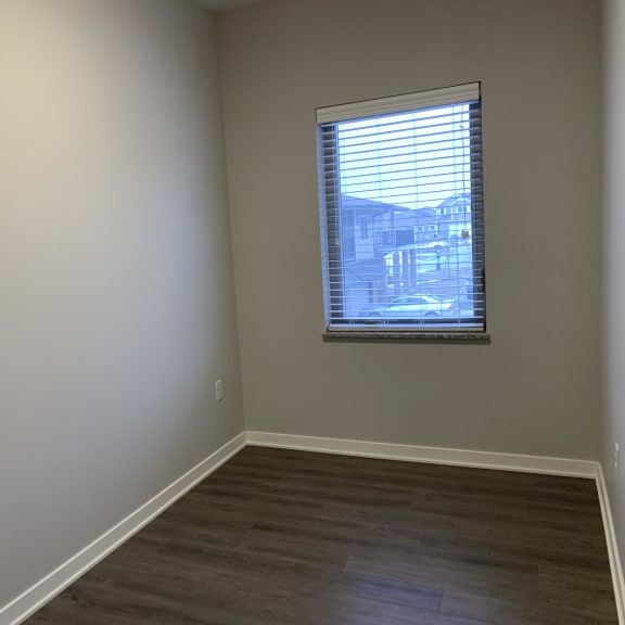 Thumbnail 9 of 21 A room with a window and wooden flooring.