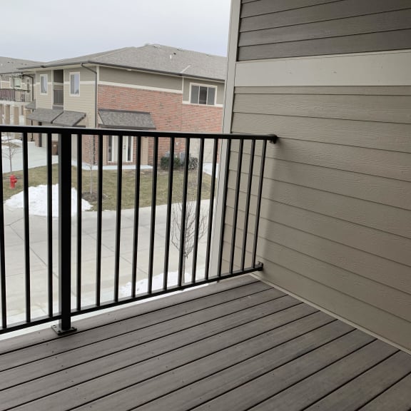Thumbnail 14 of 21 A balcony with a black railing and wooden floor.