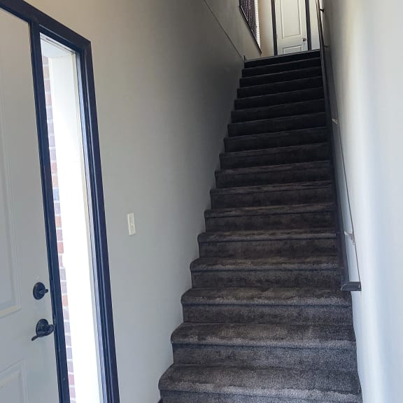 Thumbnail 23 of 23 A staircase with a carpeted runner and a black handrail.