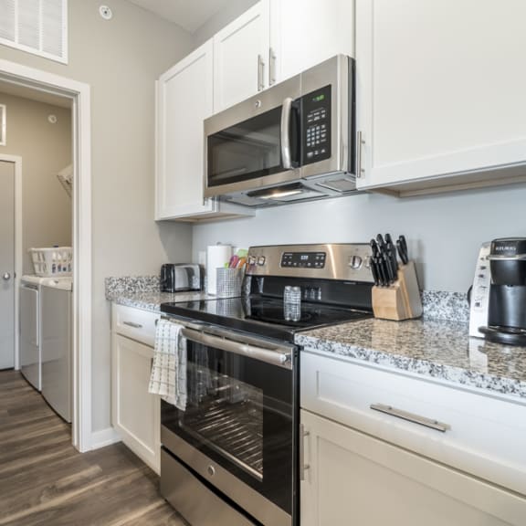 Thumbnail 7 of 23 A kitchen with a stove top oven and microwave.