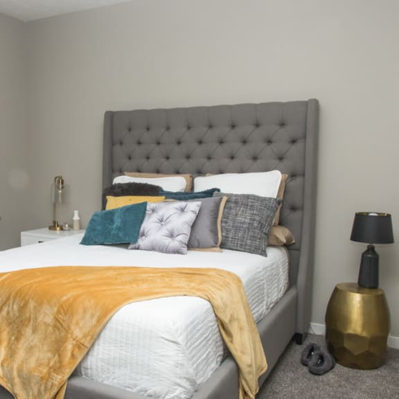 Thumbnail 9 of 13 A bedroom with a bed covered in a white comforter and a yellow throw.