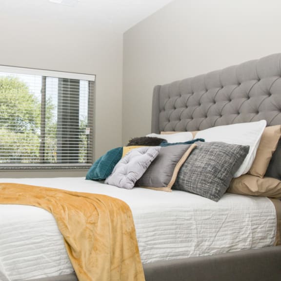 Thumbnail 10 of 13 A bedroom with a large bed and a window with blinds.
