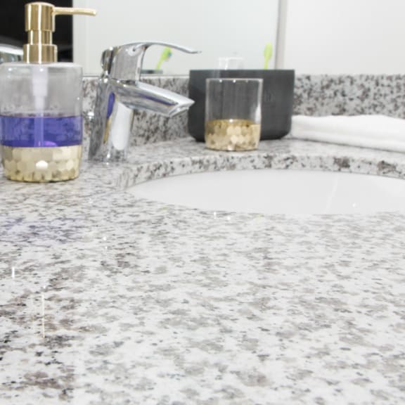 Thumbnail 12 of 13 A bathroom counter with a soap dispenser and a sink.