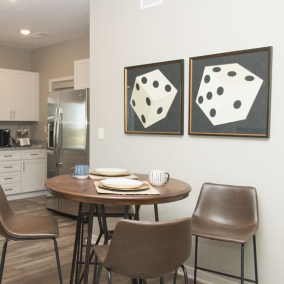 Thumbnail 8 of 13 A kitchen with a table and chairs and two paintings on the wall.