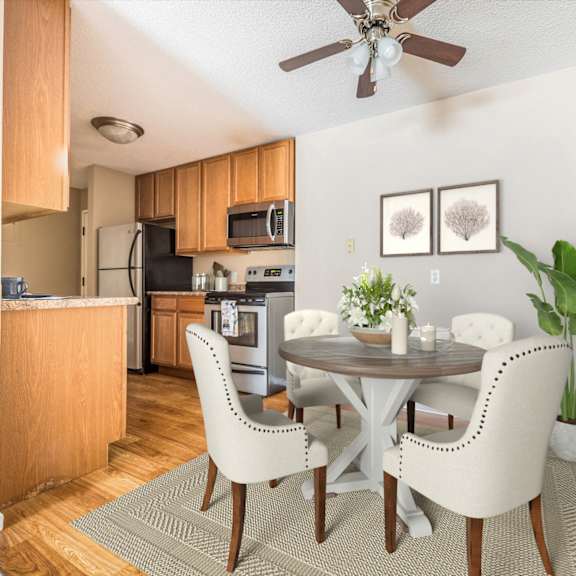 a dining area with a table and chairs and a kitchen in the background at heritage hills apartments, bloomington