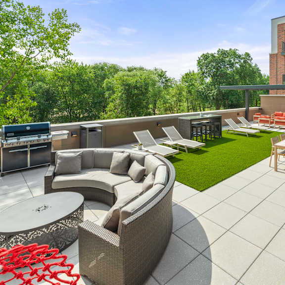 a roof-top terrace with a grilling station, fire pits, a comfortable seating area, chairs, tables, and lounge chairs on artificial turf. at keva flats, pennsylvania
