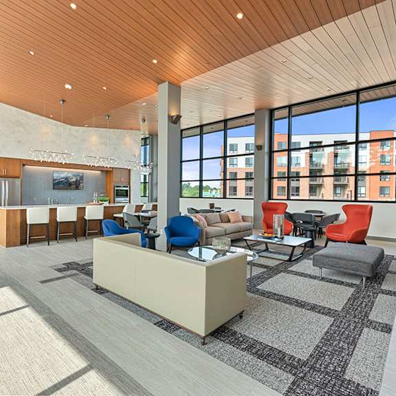 the lower level of a 2-story clubhouse with high ceilings, large panoramic windows, a community kitchen, and a comfortable lounge area. at keva flats, pennsylvania