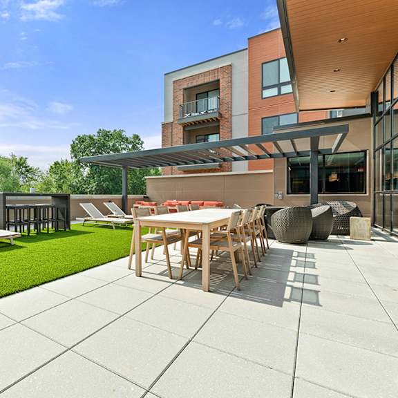 a roof-top terrace with a grilling station, fire pits, a comfortable seating area, chairs, tables, and lounge chairs on artificial turf. at keva flats, exton, 19341