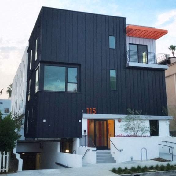 a modern black building with a red roof and a white staircase.