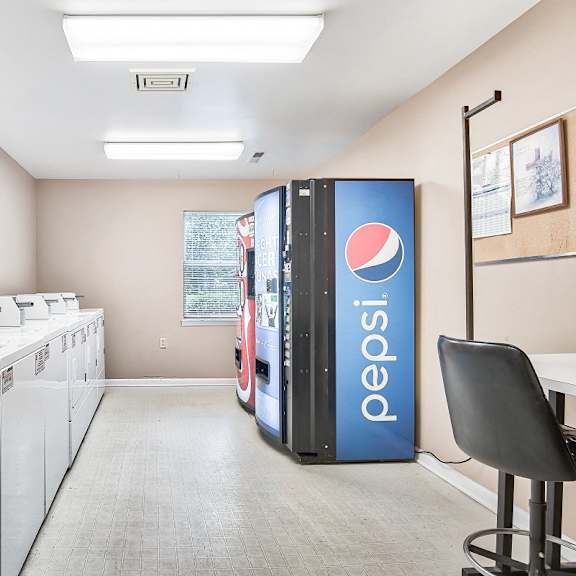 laundry facilities with soda machines and a folding table