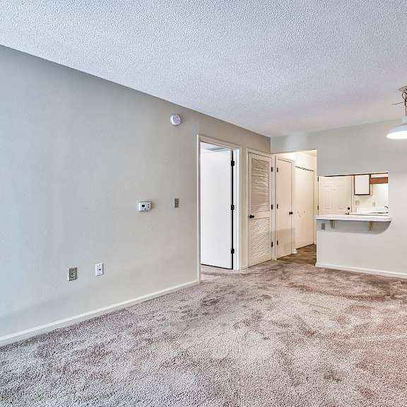 carpeted living room with view of kitchen through a bar