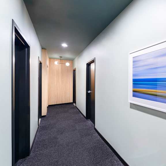 a hallway with a painting on the wall and a carpet on the floor.