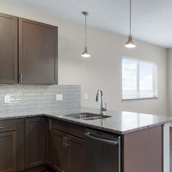 Thumbnail 3 of 19 The 2 bedroom Marigold with den floor plan at WH Flats features an open eat-in kitchen area with granite countertops and large peninsula.