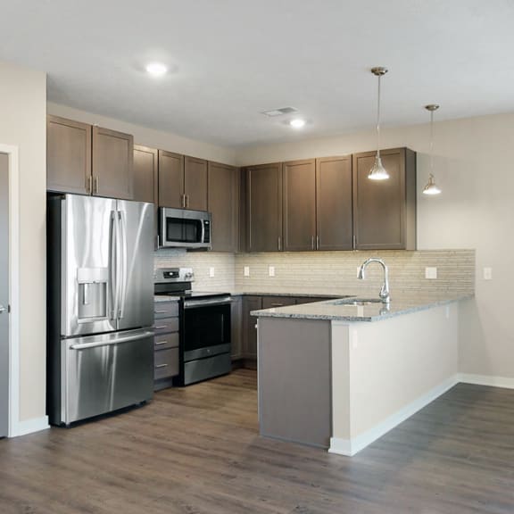 Thumbnail 2 of 19 The 2 bedroom Marigold with den floor plan at WH Flats features an open kitchen with granite countertops and large peninsula.