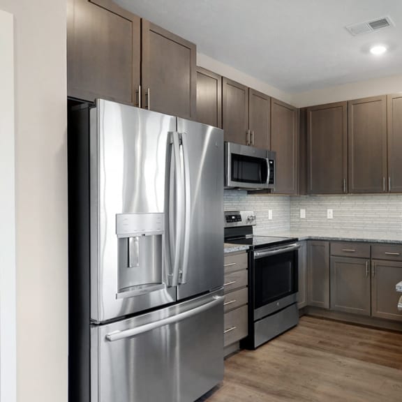 Thumbnail 5 of 19 The 2 bedroom Marigold with den floor plan at WH Flats features an stainless steel appliances, granite countertops and large peninsula.