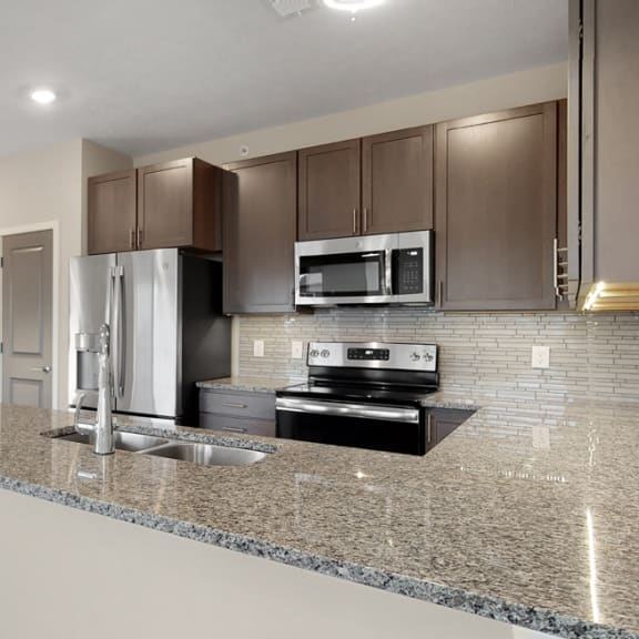 Thumbnail 4 of 19 The 2 bedroom Marigold with den floor plan at WH Flats features an stainless steel appliances, granite countertops and large peninsula.