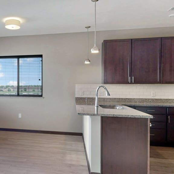 Thumbnail 4 of 24 The 2 bedroom Snowdrop with den floor plan at WH Flats features an open eat-in kitchen area with granite countertops and large peninsula.