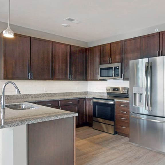 Thumbnail 2 of 24 The 2 bedroom Snowdrop with den floor plan at WH Flats features an open eat-in kitchen area with granite countertops and large peninsula.