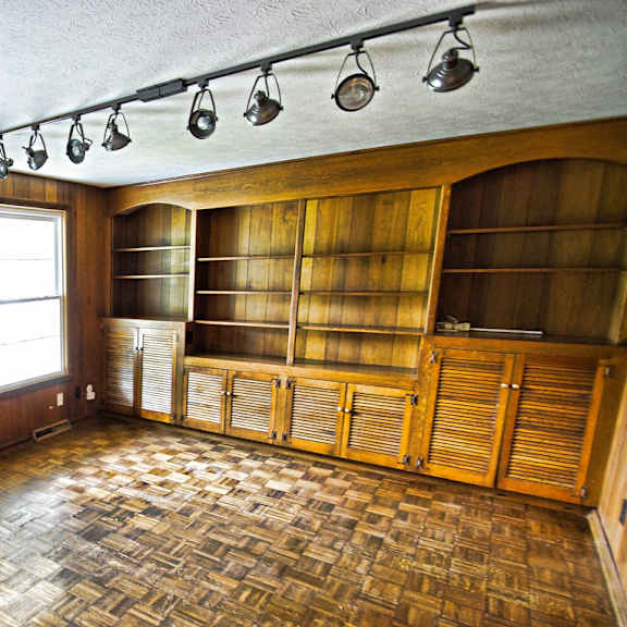 a room with wooden walls and a checkered floor and built in bookcase.