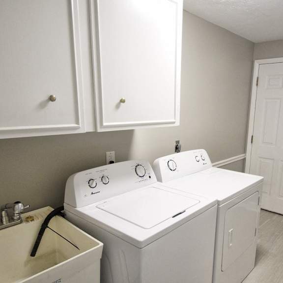 a white washer and dryer in a laundry room with white cabinets..