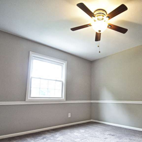 a room with a ceiling fan and a window..