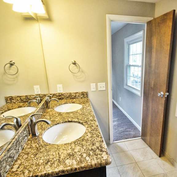 a bathroom with a granite countertop and double sinks..
