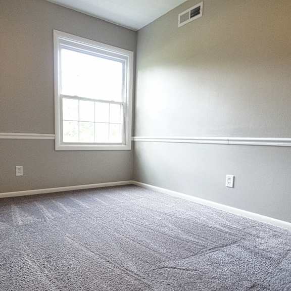 a room with a carpeted floor and a window..