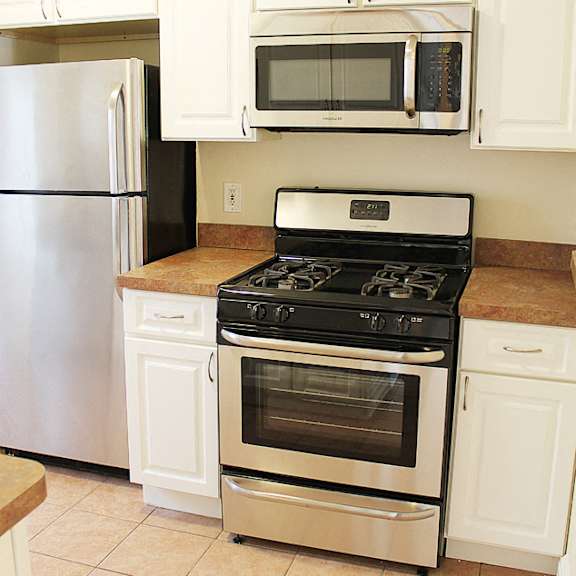 a kitchen with a stove, refrigerator, and microwave.
