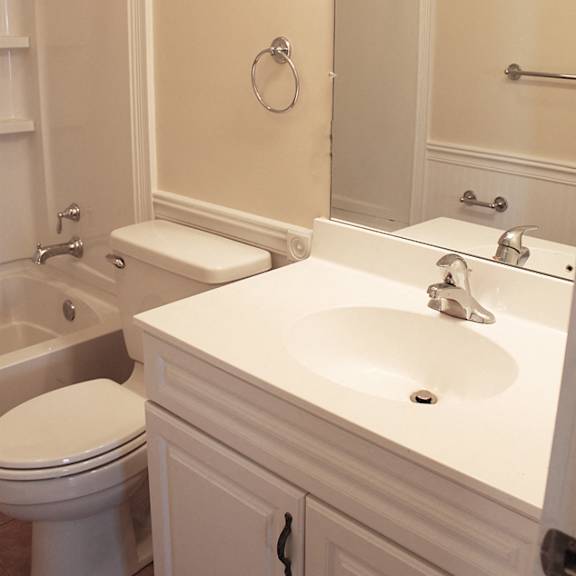a white bathroom with a toilet, sink, and mirror.