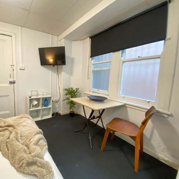 a room with a bed and a desk and a tv