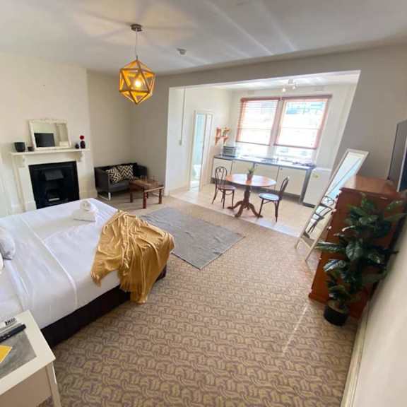 a bedroom with a bed and a living room with a desk and a window