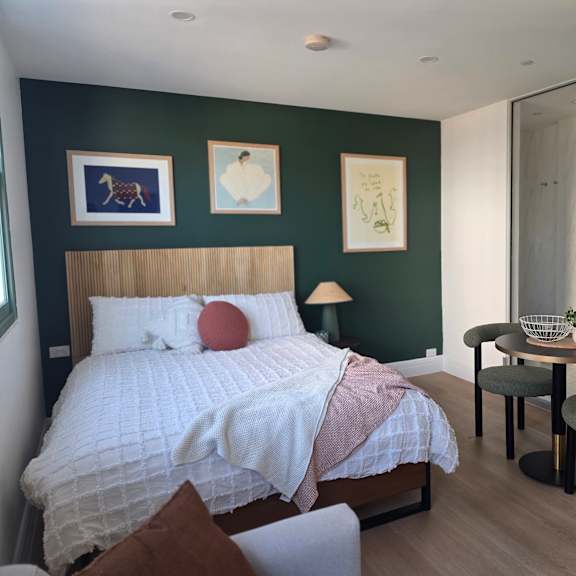 a bedroom with a bed, a table and chairs, and pictures on the wall.