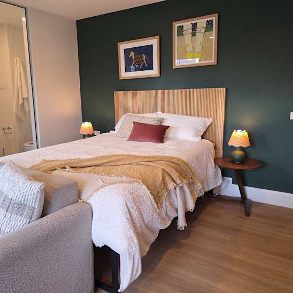 a bedroom with a bed, a chair, and a painting on the wall.