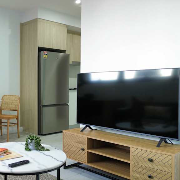 a living room with a green couch, a white coffee table, a tv, and a painting on the wall.