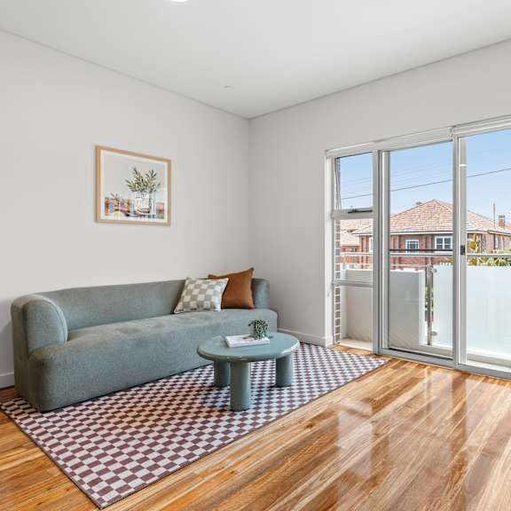 a living room with a grey couch, a coffee table, and a painting on the wall.