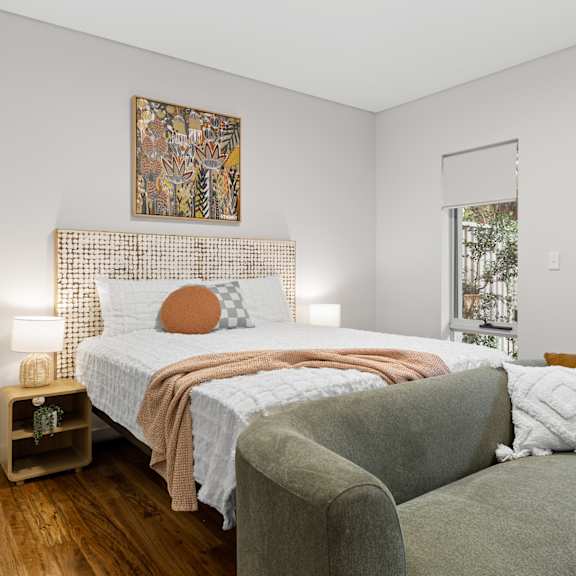 a bedroom with a bed, a couch, and a painting on the wall.