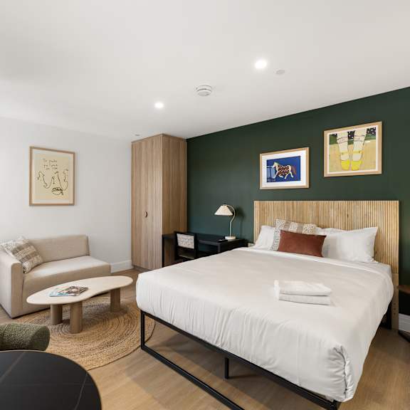 a bedroom with a large bed, a chair, a sofa, and a lamp.