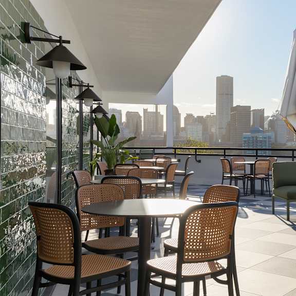 a patio with tables and chairs overlooking a city skyline.