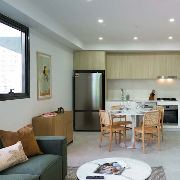 a modern living room with a green couch and a dining table set up.