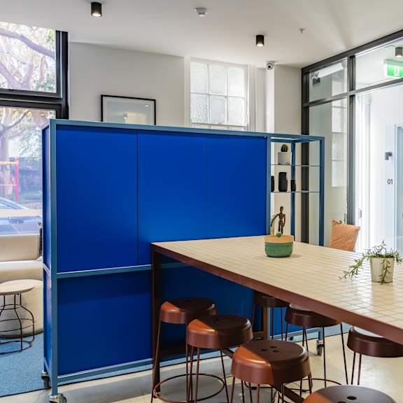 a communal table and stools in a room with glass doors