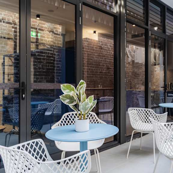 a patio with blue tables and chairs outside of a building