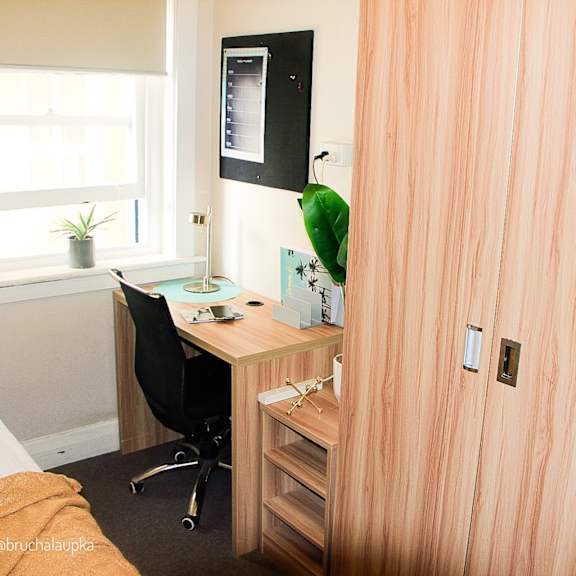 a small bedroom with a desk and a window