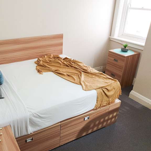 a bedroom with a bed with a wooden headboard and white bedding