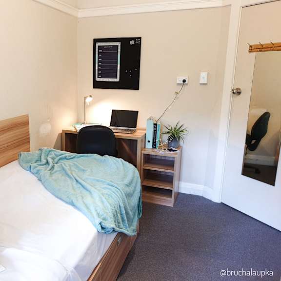 a bedroom with a bed and a desk with a laptop