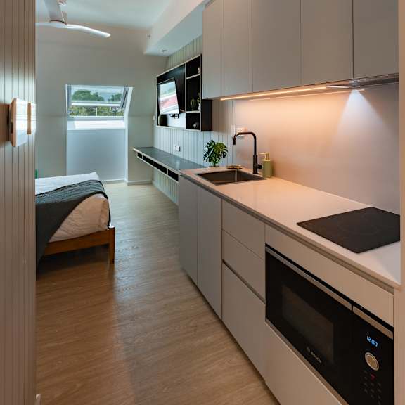 a kitchen with white cabinets and a sink and a bed