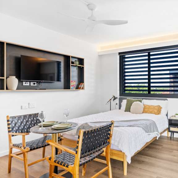 a bedroom with a bed, chair, and a television.
