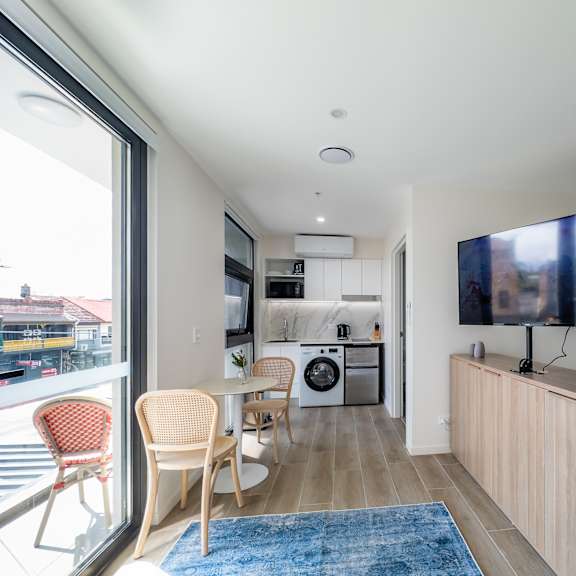 a living room with a tv and a kitchen with a table and chairs