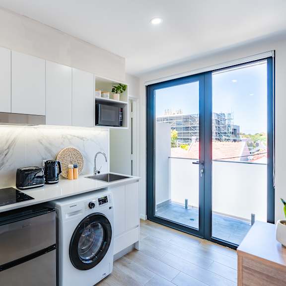 a kitchen with a washing machine and a door to a balcony